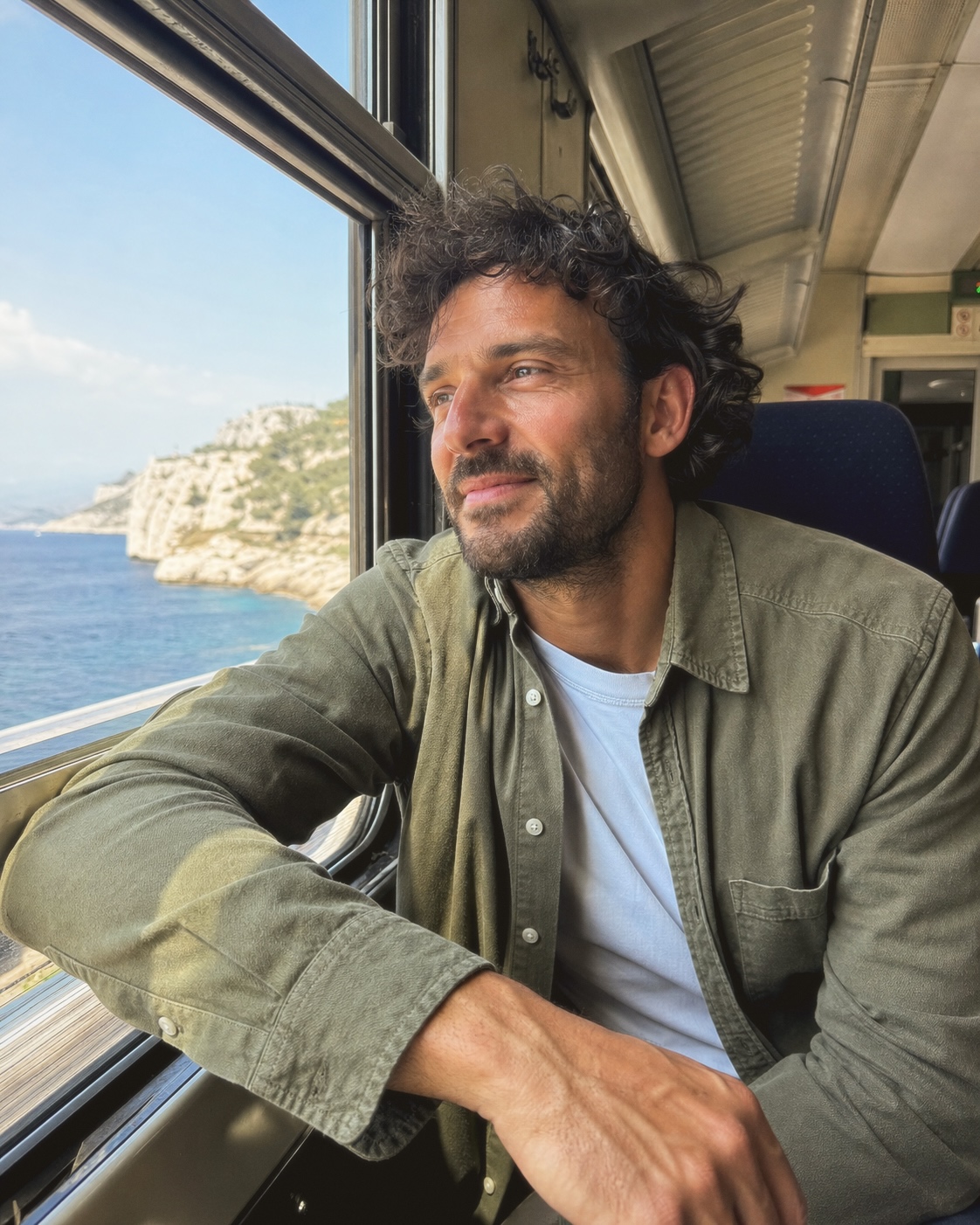 An adult man looking from a coastal train window, finished with Fold II.