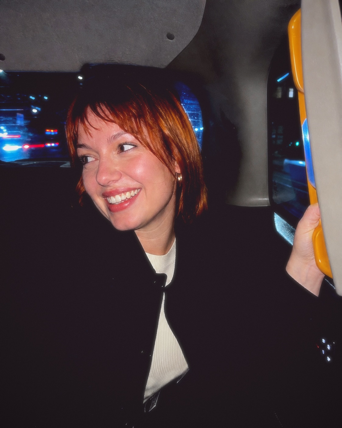 An adult woman laughing in the back of a city taxi, finished with Fold I.