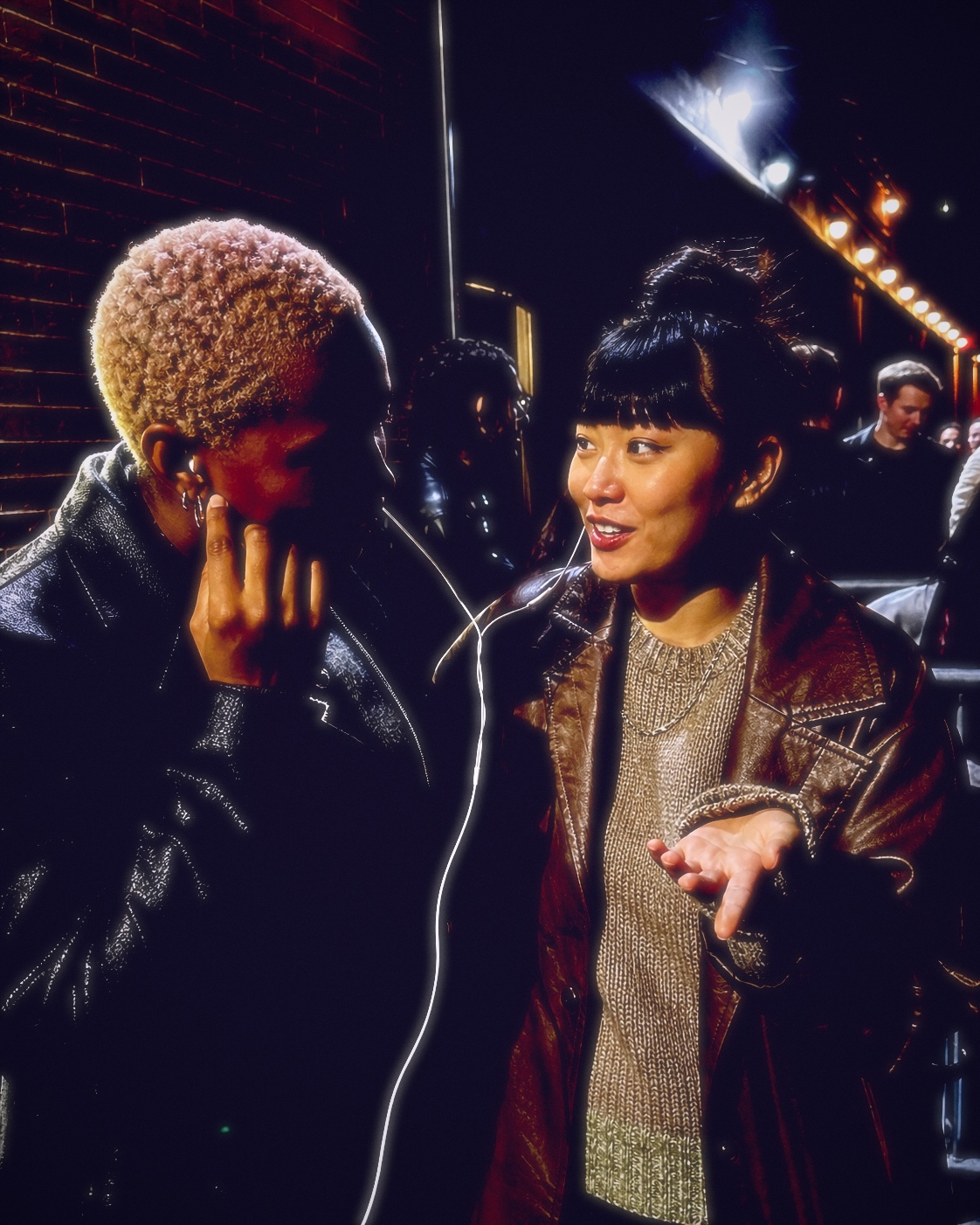 Two adult friends sharing headphones outside a venue, finished with Fold III.